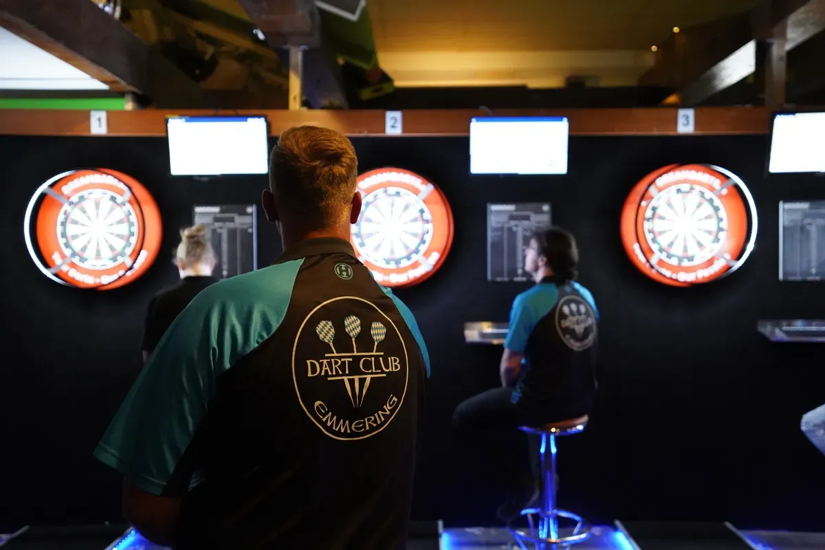 Ein Spieler im Vereinsshirt von hinten vor den Dartboards