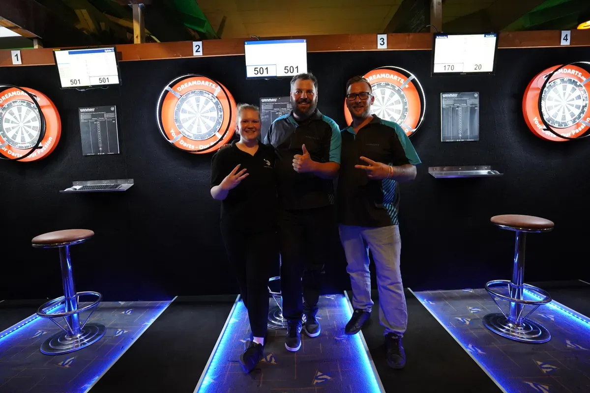 Drei Finalisten der Abschlusscompetition posieren vor den Dartboards